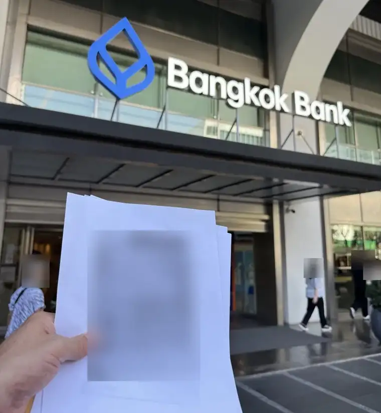 Outside a Bangkok Bank branch in Bangkok with a client’s document copies; the documents and passers-by are blurred