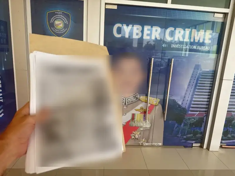 Outside the Cyber Crime Investigation Bureau in Bangkok with document copies; the documents and the portrait on the door are blurred