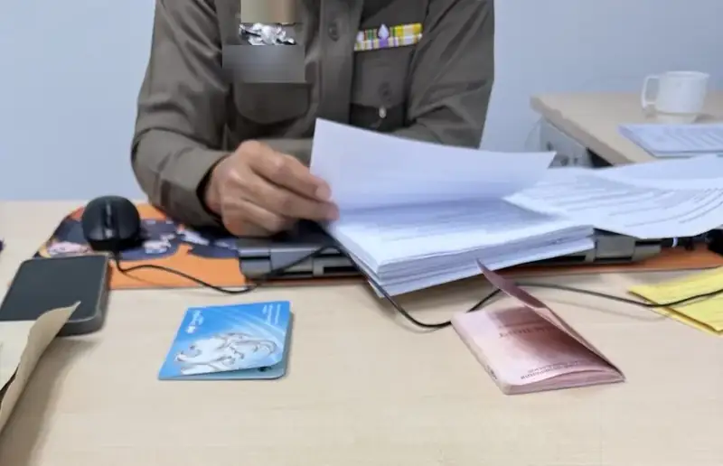 A police officer reviewing documents at his desk while the account holder gives a statement; the officer’s name tag is hidden